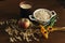 Oat ears stems and oat flakes in a white pot, marigold flowers and cup of milk and apple on dark brown wood table. Top view. oat f