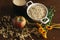 Oat ears stems and oat flakes in a white pot, marigold flowers and cup of milk and apple on dark brown wood table. Top view. oat f