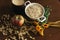 Oat ears stems and oat flakes in a white pot, marigold flowers and cup of milk and apple on dark brown wood table. Top view. oat f