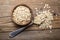 Oat flakes in bowl with spoon on wooden background, top view.