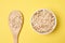 Oat flakes. Healthy eating. Wooden spoon. Yellow background