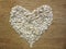 Oat flakes pile in a heart shape on a wooden background