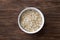 Oat flakes, rolled oatmeal in a white bowl on a wooden table