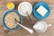 Oat flakes, sugar in bowls, salt shaker, milk in pitcher, butter on saucer on table. Top view