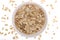 Oat flakes, uncooked oats in bowl with poon and wheat ears on white background. Concept of healthy eating, vegan food, healthy foo