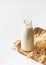 Oat milk in glass bottle with flakes and spike or ears of grain on white background