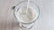 Oat milk in transparent cup with handle. Vegan alternative to cow dairy products. Opaque creamy drink is poured into glass. Close-