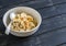 Oatmeal with banana, caramel sauce and pecan nuts in a white bowl on a dark wooden surface