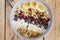 Oatmeal with bananas, cranberry, chia seeds, coconut shreds, almonds. Healthy breakfast concept. Rustic wooden background.