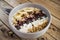 Oatmeal with bananas, cranberry, chia seeds, coconut shreds, almonds. Healthy breakfast concept. Rustic wooden background.