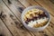 Oatmeal with bananas, cranberry, chia seeds, coconut shreds, almonds. Healthy breakfast concept. Rustic wooden background.