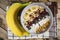 Oatmeal with bananas, cranberry, chia seeds, coconut shreds, almonds. Healthy breakfast concept. Rustic wooden background.