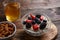 Oatmeal with berries and almonds, glass of compote on wooden background