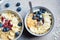 Oatmeal bowl with banana, berries, hemp seeds and coconut slices, top view. Healthy vegan breakfast concept