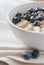 Oatmeal in bowl in close up. Healthy breakfast: Porridge oatmeal with banana, blueberry and walnuts in white bowl on linen napki