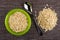 Oatmeal in bowl, spoon, heap of oatmeal on mat. Top view