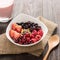 Oatmeal in bowl topped with fresh blueberries, cranberries, strawberries, raspberries, blackberries and berry smoothie.