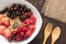 Oatmeal in bowl topped with fresh blueberries, cranberries, strawberries, raspberries, blackberries for healthy breakfast.