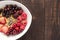 Oatmeal in bowl topped with fresh blueberries, cranberries, strawberries, raspberries, blackberries for healthy breakfast.