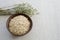 Oatmeal in a brown ceramic bowl with on a background of green ripe ears of oats on a linen tablecloth