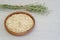 Oatmeal in a brown ceramic bowl with on a background of green ripe ears of oats on a linen tablecloth