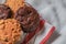 Oatmeal cookie milk cookie and chocolate chip nut cookie on grate metal red and white napkin black background.