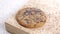 Oatmeal cookie with sprinkling dry poppy seeds in slow motion. On a rustic wooden board.