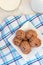 oatmeal cookies on a square white plate on a white waffle towel with blue stripes, a cup with milk