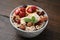 Oatmeal with freeze dried fruits, nuts and mint on wooden table