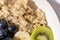 oatmeal, kiwi, berries, blueberries ready to eat on the white table and white plate