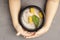 Oatmeal porridge bowl with pineapple pieces in hands. Hands holding bowl of oat porridge with mint leaf. Selective focus