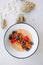 Oatmeal porridge in bowl topped with fresh blueberries, cranberries and homemade crunchy granola