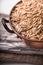 Oats in a copper bowl on a wooden stand closeup