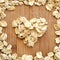 Oats in heart shape arranged on wood grain in square format for social media, banners and backgrounds.