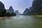 Oats with tourists cruising in the Li River with the tall limestone peaks in the background near Yangshuo in China