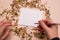 Oats, wheat, corn, sunflower seeds and blank card in hand on pink background.