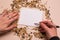 Oats, wheat, corn, sunflower seeds and blank card in hand on pink background.