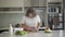 Obese Caucasian woman cooking fresh salad in kitchen. Portrait of overweight young concentrated lady cutting vegetables