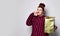 Obese lady in striped dress, crown, earrings. Holding golden gift box tied with ribbon and bow, posing isolated on white