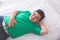 Obese man having stomach ache while laying on a bed