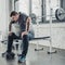 Obese man sitting on bench after exercising with dumbbells at gym