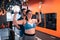 Obese woman doing exercises with barbells with help of trainer