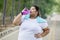 Obese woman drinking water on the road
