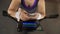 Obese woman scrolling on cellphone while riding exercise bike, fitness app