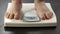 Obese woman standing on scales to check body weight, overweight problem, closeup