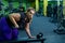 An obese woman is training with dumbbells on a bench in the gym. The fat blonde is losing weight with the help of
