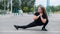 Obese young caucasian woman doing side lunges. Fat beautiful smiling girl in a black tracksuit is engaged in fitness