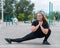 Obese young caucasian woman doing side lunges. Fat beautiful smiling girl in a black tracksuit is engaged in fitness