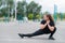 Obese young caucasian woman doing side lunges. Fat beautiful smiling girl in a black tracksuit is engaged in fitness