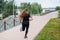 An obese young woman jogging outdoors. Fat beautiful smiling girl in a black tracksuit is engaged in fitness for weight